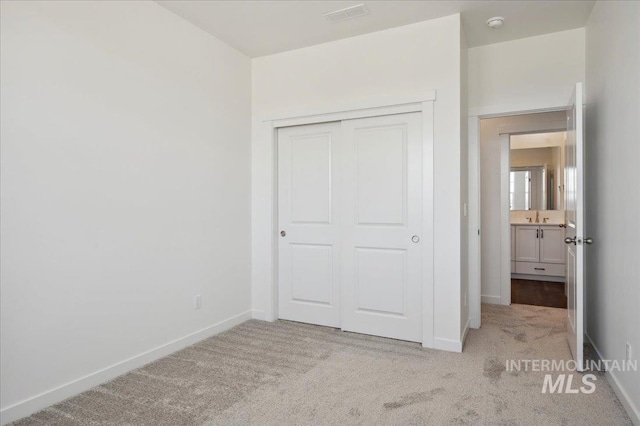 unfurnished bedroom with carpet floors, a closet, baseboards, and visible vents