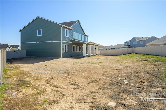 rear view of house featuring a fenced backyard