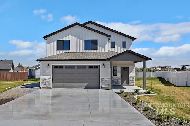 view of front of property featuring board and batten siding, fence, a garage, driveway, and a front yard