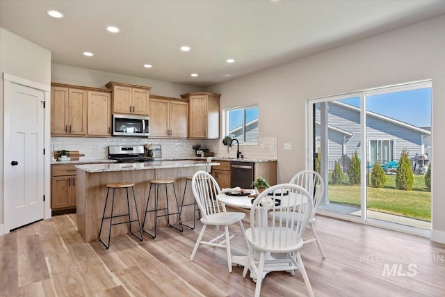 kitchen featuring tasteful backsplash, stainless steel appliances, light wood-type flooring, and a kitchen island