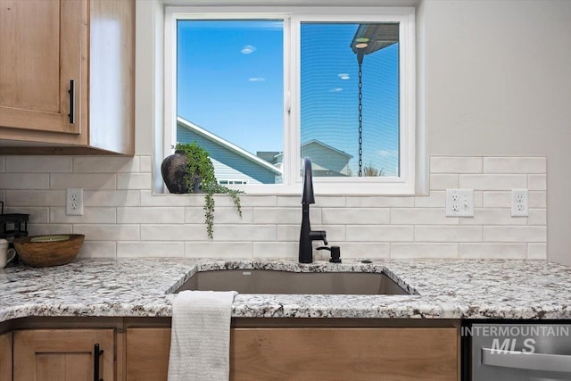 details with light stone countertops, dishwashing machine, backsplash, and a sink