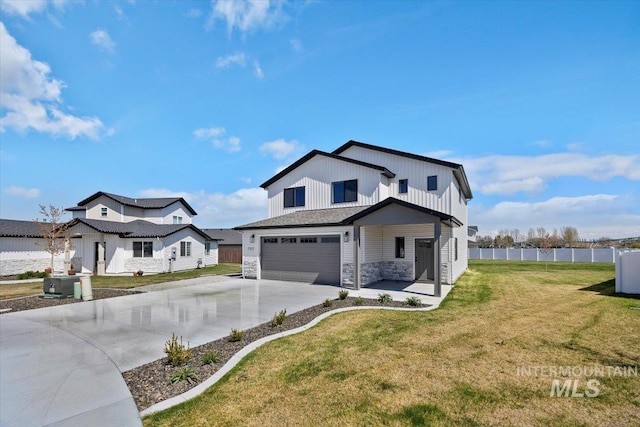 traditional-style home with fence, stone siding, a front lawn, concrete driveway, and an attached garage