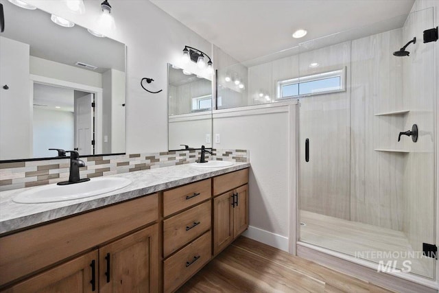 bathroom with visible vents, a stall shower, backsplash, and a sink