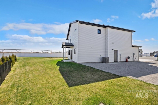 back of property with a lawn, a patio, central AC, and fence