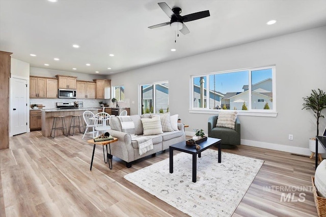 living room featuring light wood-type flooring, recessed lighting, a ceiling fan, and baseboards