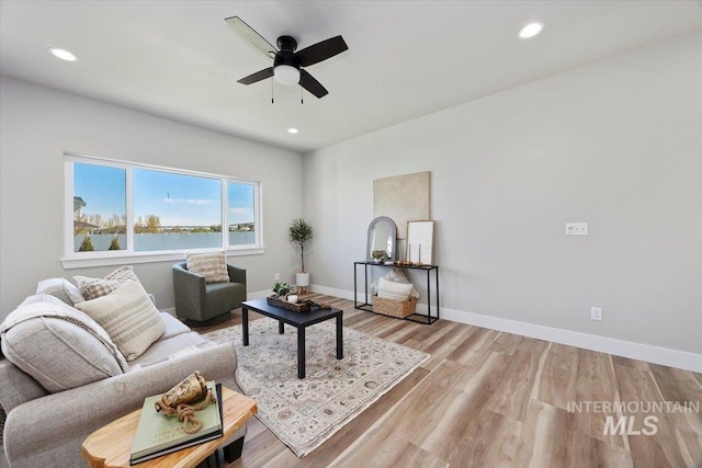 living area with a water view, light wood-type flooring, a ceiling fan, and recessed lighting
