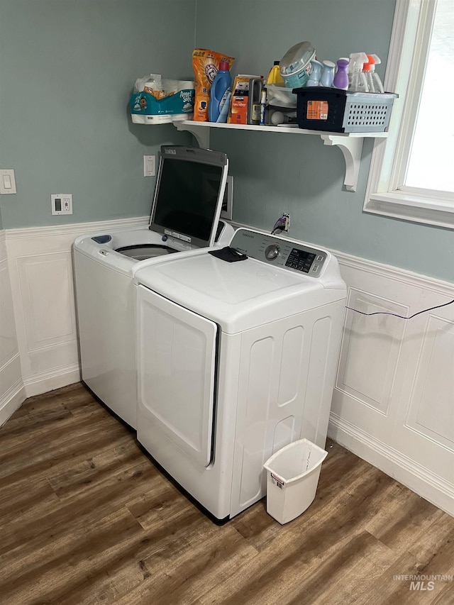 washroom featuring a decorative wall, washing machine and dryer, a wainscoted wall, and wood finished floors