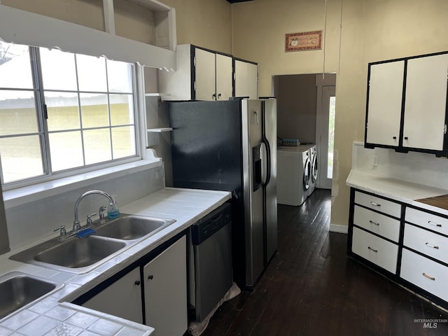 kitchen with separate washer and dryer, stainless steel dishwasher, white cabinetry, dark wood finished floors, and a sink
