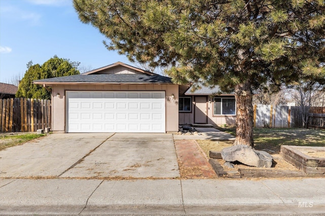 ranch-style house featuring an attached garage, a shingled roof, driveway, and fence