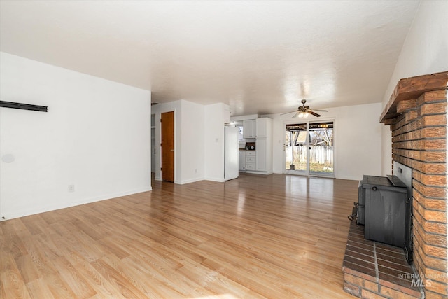 unfurnished living room with baseboards, light wood finished floors, and ceiling fan