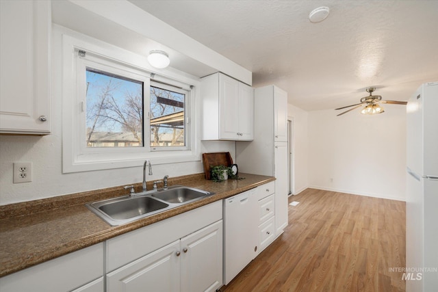 kitchen featuring a sink, white appliances, dark countertops, and white cabinets