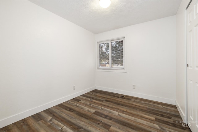 unfurnished room with baseboards, dark wood-style flooring, and a textured ceiling