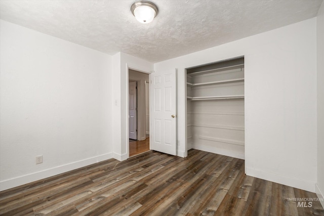 unfurnished bedroom with a closet, a textured ceiling, dark wood-type flooring, and baseboards