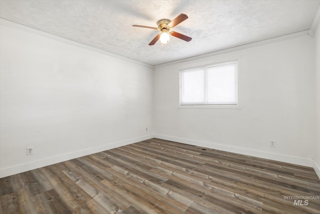 unfurnished room featuring baseboards, wood finished floors, a textured ceiling, and ornamental molding