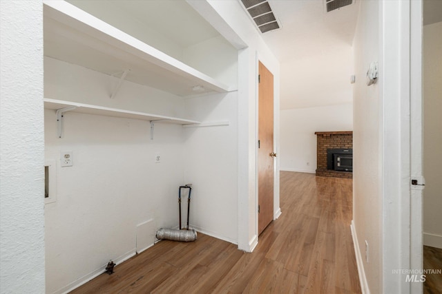 laundry area with visible vents, baseboards, wood finished floors, and a fireplace