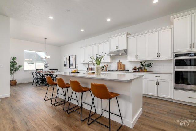 kitchen featuring light countertops, appliances with stainless steel finishes, white cabinets, and under cabinet range hood