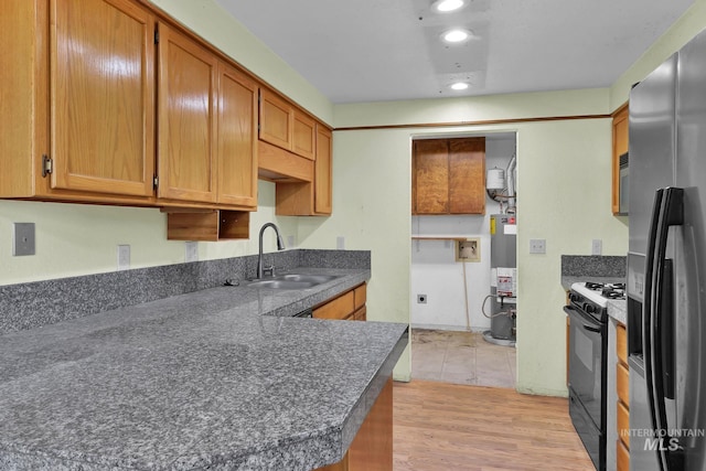 kitchen with water heater, sink, stainless steel fridge, light hardwood / wood-style floors, and gas stove