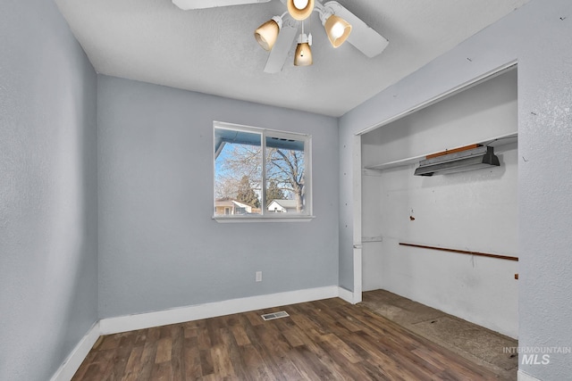 unfurnished bedroom with a closet, a textured ceiling, dark hardwood / wood-style floors, and ceiling fan