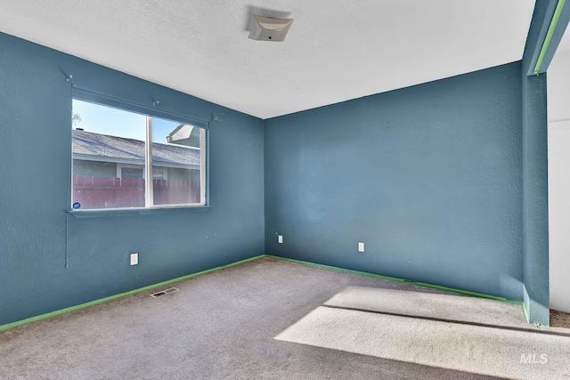 carpeted empty room with a textured ceiling