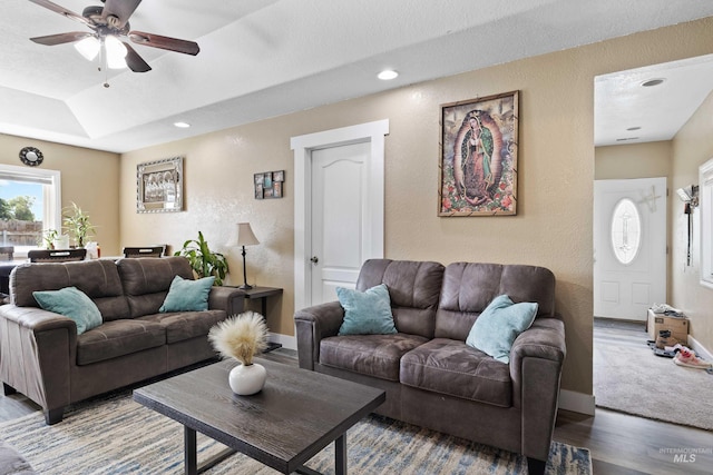 living room featuring ceiling fan, a raised ceiling, and dark hardwood / wood-style flooring