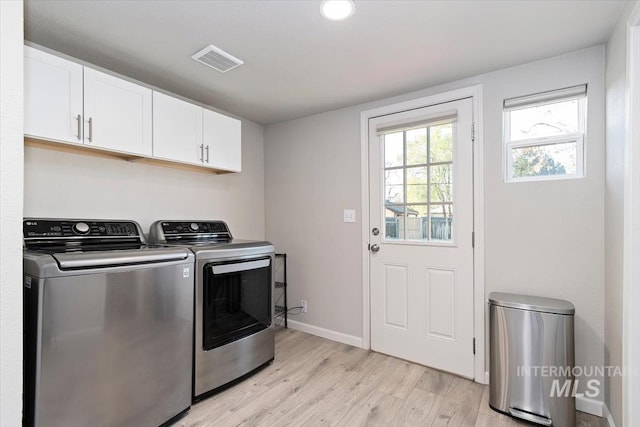 laundry area featuring washing machine and clothes dryer, baseboards, visible vents, light wood-style floors, and cabinet space