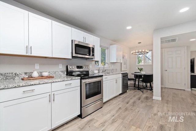kitchen featuring an inviting chandelier, stainless steel appliances, light wood-style flooring, white cabinets, and visible vents
