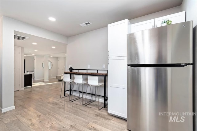 kitchen featuring freestanding refrigerator, light wood-type flooring, visible vents, and white cabinetry