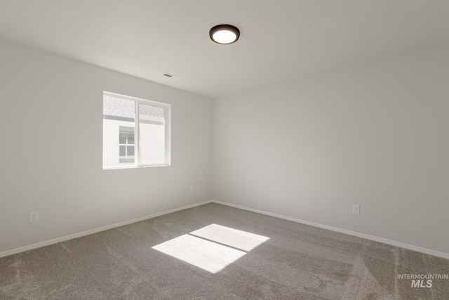 spare room with carpet, visible vents, and baseboards