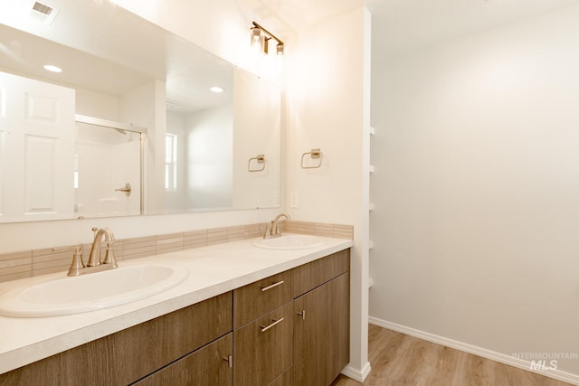 full bathroom with double vanity, visible vents, a sink, and wood finished floors