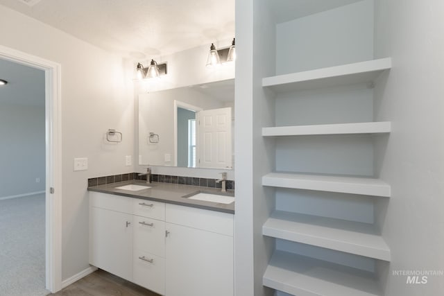 bathroom with double vanity, a sink, and baseboards