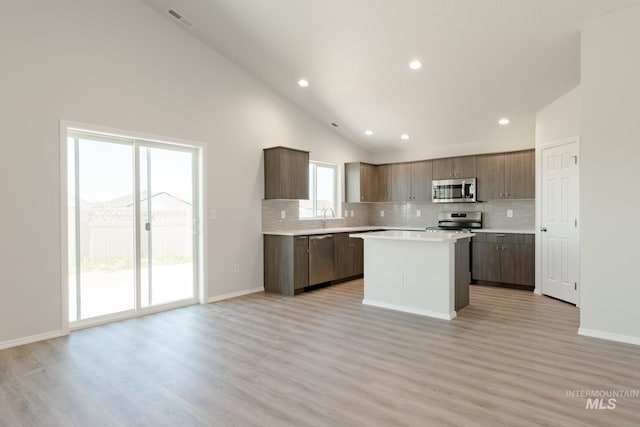 kitchen featuring light hardwood / wood-style flooring, a kitchen island, stainless steel appliances, and high vaulted ceiling