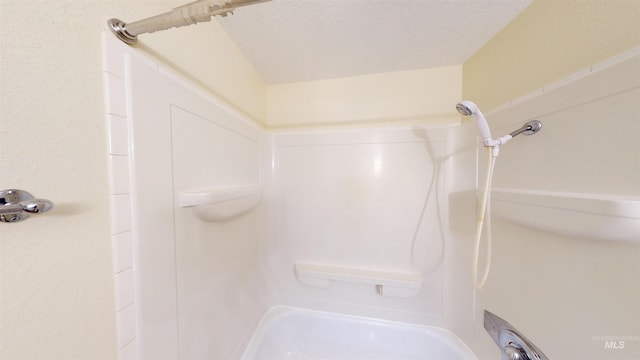 bathroom with a textured ceiling and washtub / shower combination