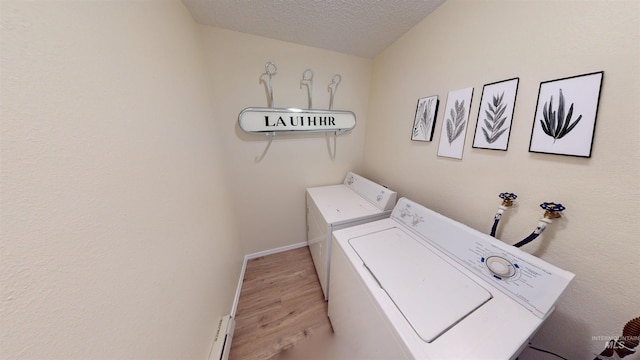 washroom with washing machine and clothes dryer, light hardwood / wood-style floors, and a textured ceiling