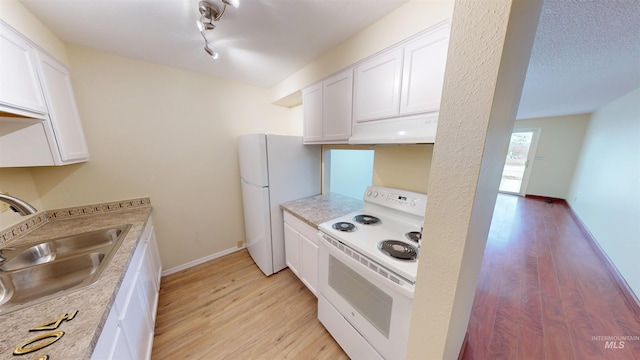 kitchen with white cabinetry, white appliances, sink, and light hardwood / wood-style floors