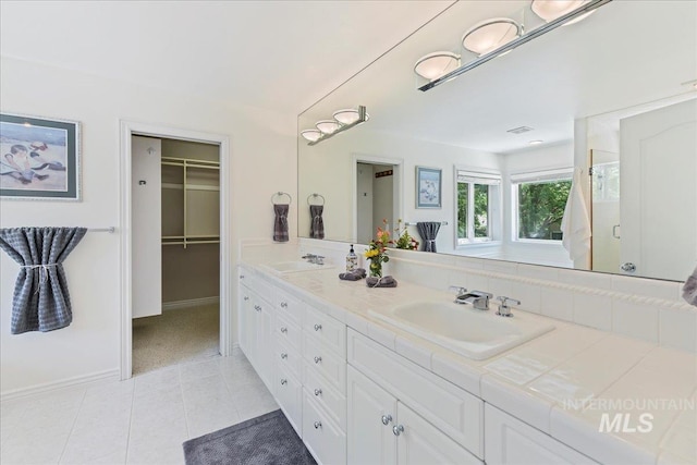 5130 N Lakemont Ln, Garden City, ID 83714 - full bathroom with tile patterned floors, double vanity, a walk in closet, baseboards, and a shower with shower door