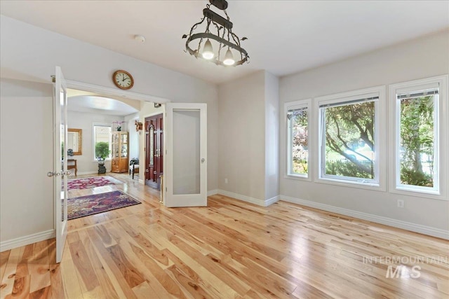 5130 N Lakemont Ln, Garden City, ID 83714 - unfurnished dining area featuring french doors, arched walkways, light wood-type flooring, and baseboards