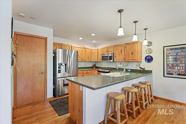 1425 Clements Rd Unit 5, Mccall, ID 83638 - kitchen with stainless steel appliances, a peninsula, light wood finished floors, dark countertops, and a sink