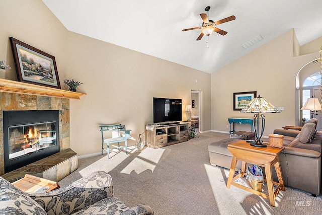 carpeted living room with a tiled fireplace, ceiling fan, and vaulted ceiling