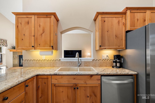 kitchen featuring sink, stainless steel appliances, backsplash, and light stone countertops