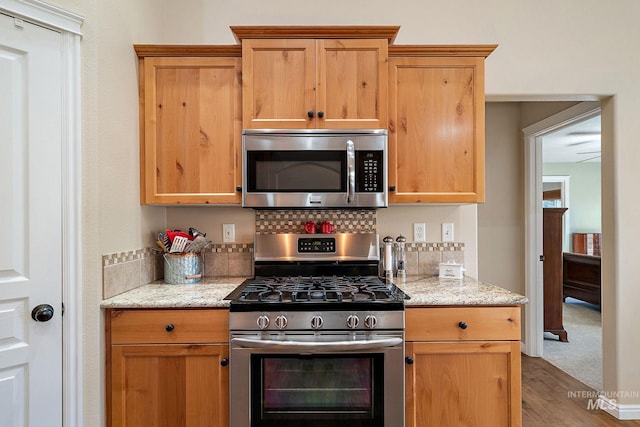 kitchen with light stone counters, stainless steel appliances, and wood-type flooring