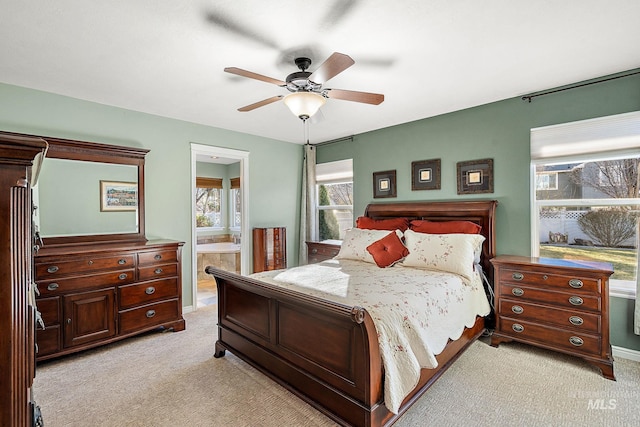 bedroom featuring ensuite bathroom, light carpet, and ceiling fan