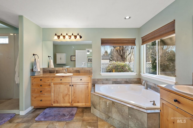 bathroom featuring tiled tub and vanity