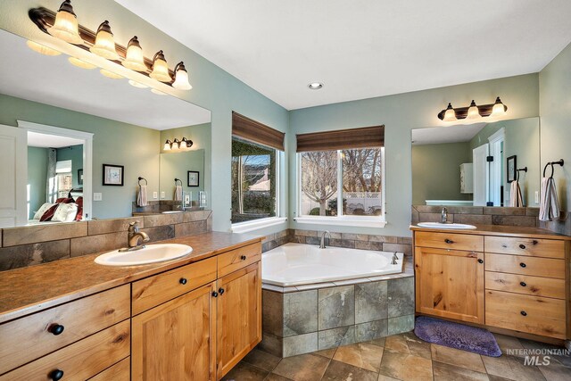 bathroom featuring a relaxing tiled tub and vanity