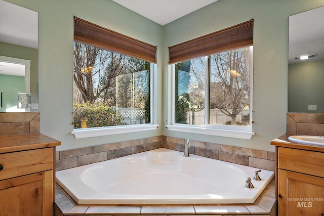 bathroom featuring tiled tub and vanity