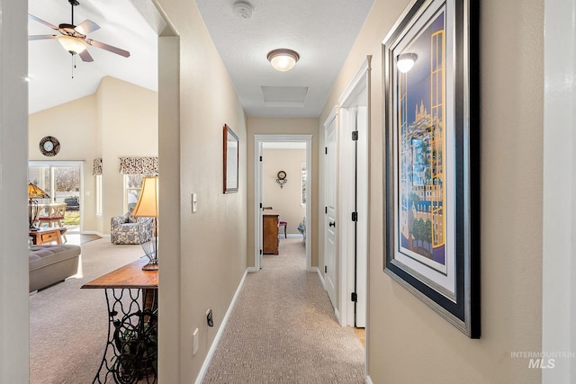 hall featuring lofted ceiling, a textured ceiling, and light carpet