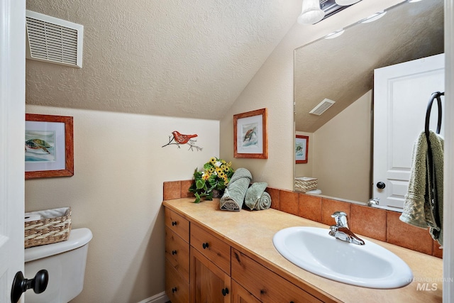 bathroom with toilet, vanity, and vaulted ceiling