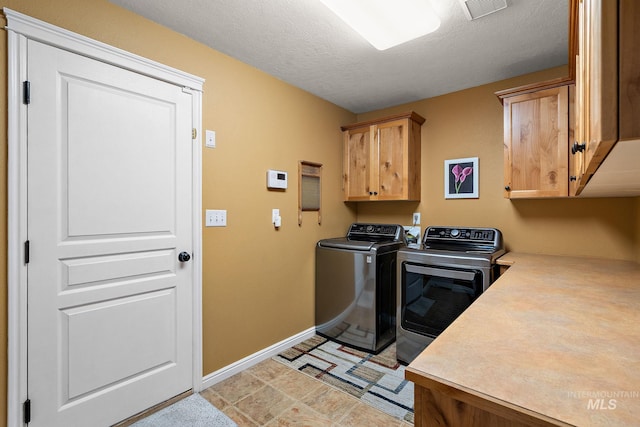 laundry area with a textured ceiling, cabinets, and independent washer and dryer