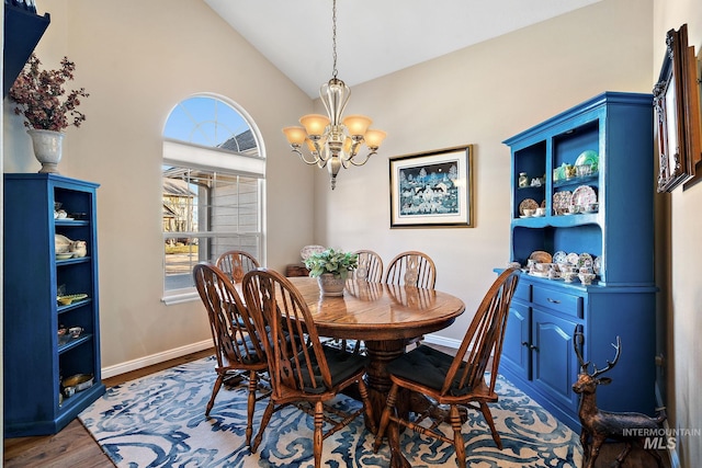 dining area with lofted ceiling, hardwood / wood-style floors, and a notable chandelier