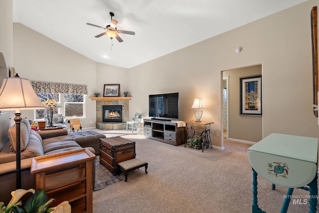 carpeted living room featuring lofted ceiling, a tiled fireplace, and ceiling fan