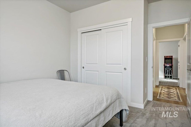 carpeted bedroom with a closet and baseboards